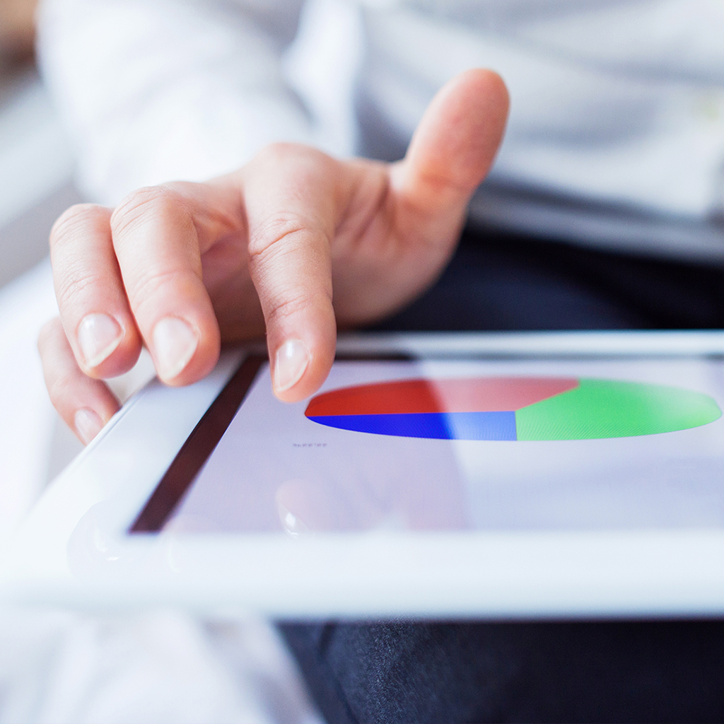 Person’s hand hovering over tablet display of pie chart.