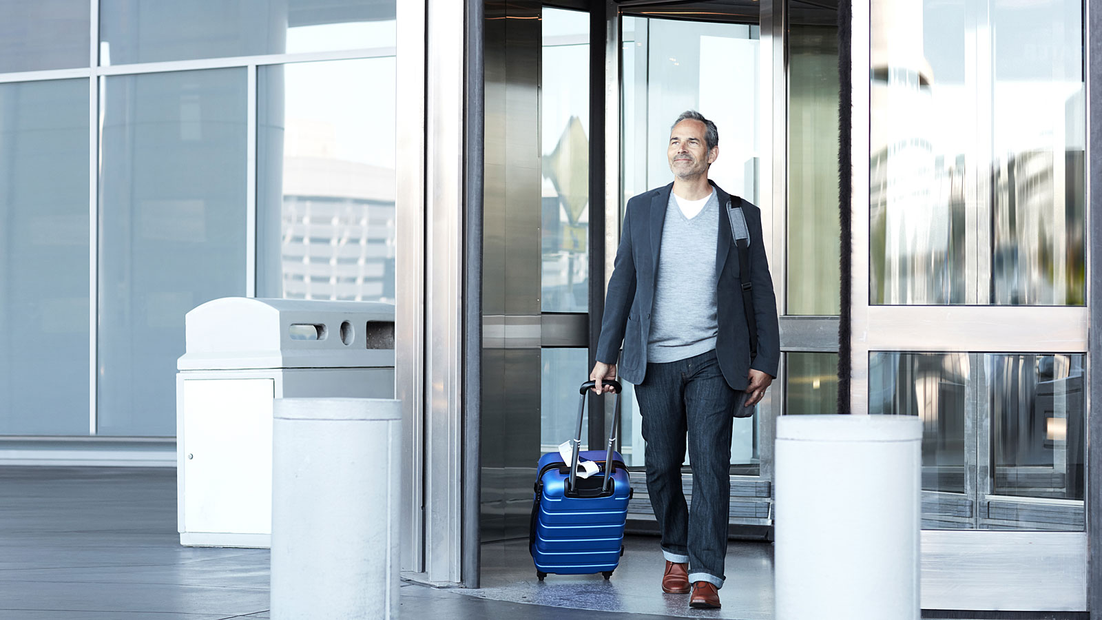 man with luggage going outside the airport