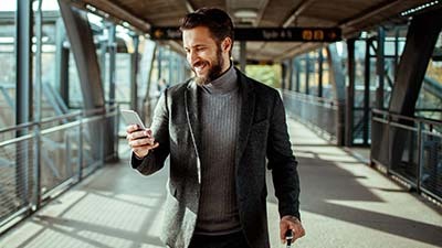 Hombre sonriente enviando usando su celular en la calle